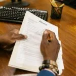 Osoba podpisuje dokumenty prawne przy biurku w kancelarii