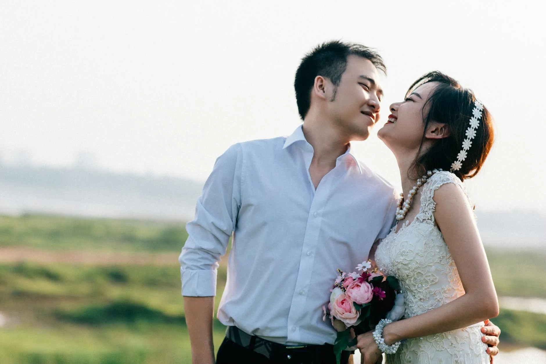 Para młoda obejmuje się podczas plenerowego ślubu w słońcu