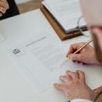 Zbliżenie na dłoń podpisującą dokument rozwodowy na biurku