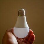 Dłoń trzymająca energooszczędną żarówkę LED symbolizującą zrównoważone oświetlen