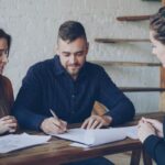 Młode małżeństwo omawia dokumenty majątkowe z doradcą w biurze