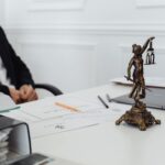 Biurko prawnika z figurą Temidy, dokumentami i laptopem