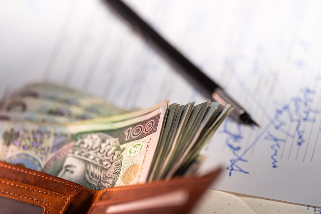 Polskie banknoty złotowe, długopis i dokument dotyczący kredytu hipotecznego