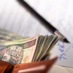 Sprzedaż mieszkania z kredytem hipotecznym – jakie formalności u notariusza? Polskie banknoty złotowe, długopis i dokument dotyczący kredytu hipotecznego