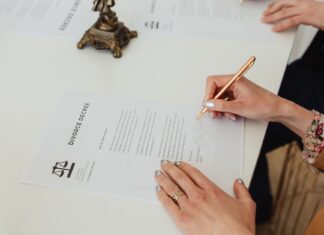 Zbliżenie dłoni podpisujących dokument rozwodowy przy biurku